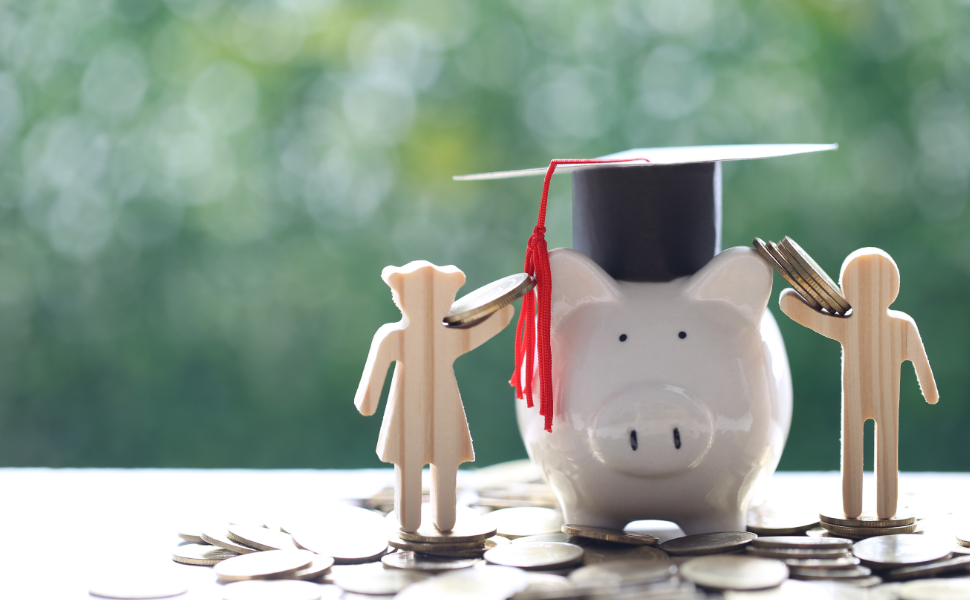 Sparschwein mit Absolventenhut und zwei Holzfiguren auf einer Oberfläche stehend