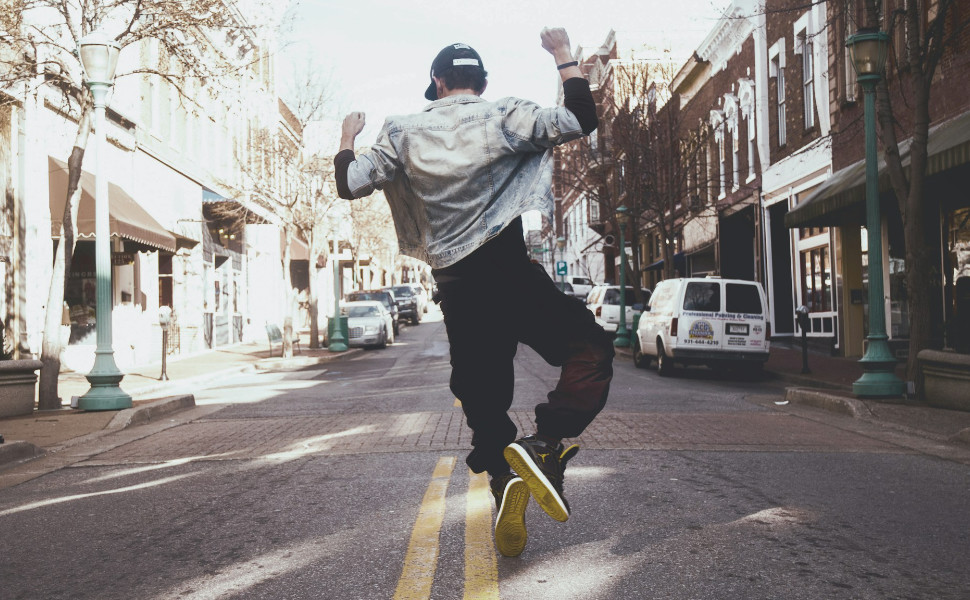 Rückenansicht eines jungen Mannes, der auf einer Straße tanzt