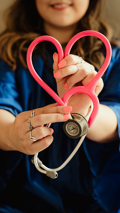 Eine Frau hält ein rosafarbenes Stehteleskop in Herzform in die Kamera.
