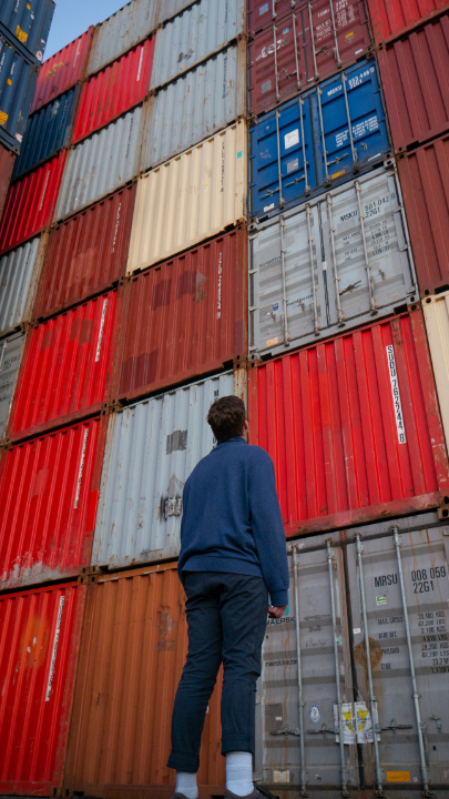Eine Person schaut auf gestapelte Schiffscontainer.