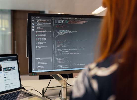 Informatikerin sitzt vor einem Bildschirm und programmiert.