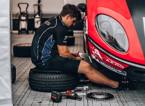 Ein Kfz-Mechatroniker schraubt an einem Auto. 