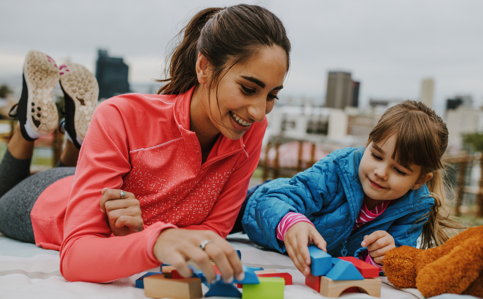Junge Frau spielt als Au Pair mit einem kleinen Mädchen Bausteine