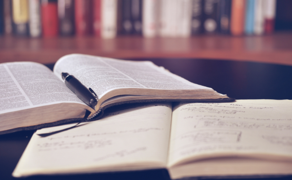 Geöffnete Bücher mit Stift in einer Bibliothek