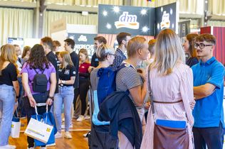 Messebsucher:innen unterhalten sich mit Ausstellenden