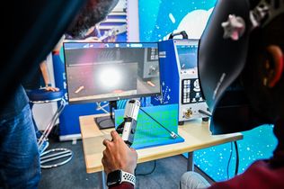 Ein junger Mann versucht sich am Schweiß-Simulator.