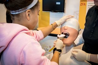 Eine Jugendliche versucht an einem künstlichen Modell, einen Zahnabdruck zu nehmen.