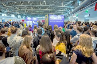 Viele junge Menschen sind in der Messehalle auf einer Einstieg Messe zu sehen