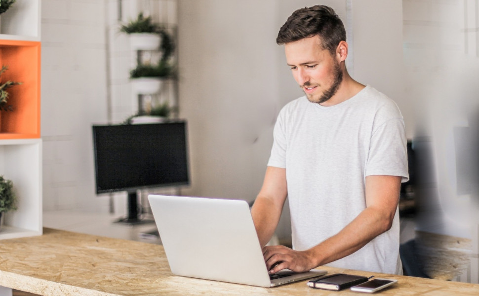 Junger Mann arbeitet am Laptop.