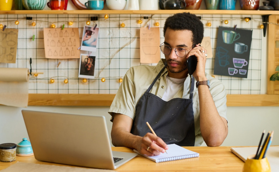 Ein junger Mann arbeitet und telefoniert.