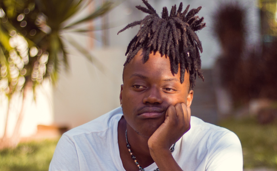 Gelangweilter junger Mann stützt den Kopf auf die Hand.